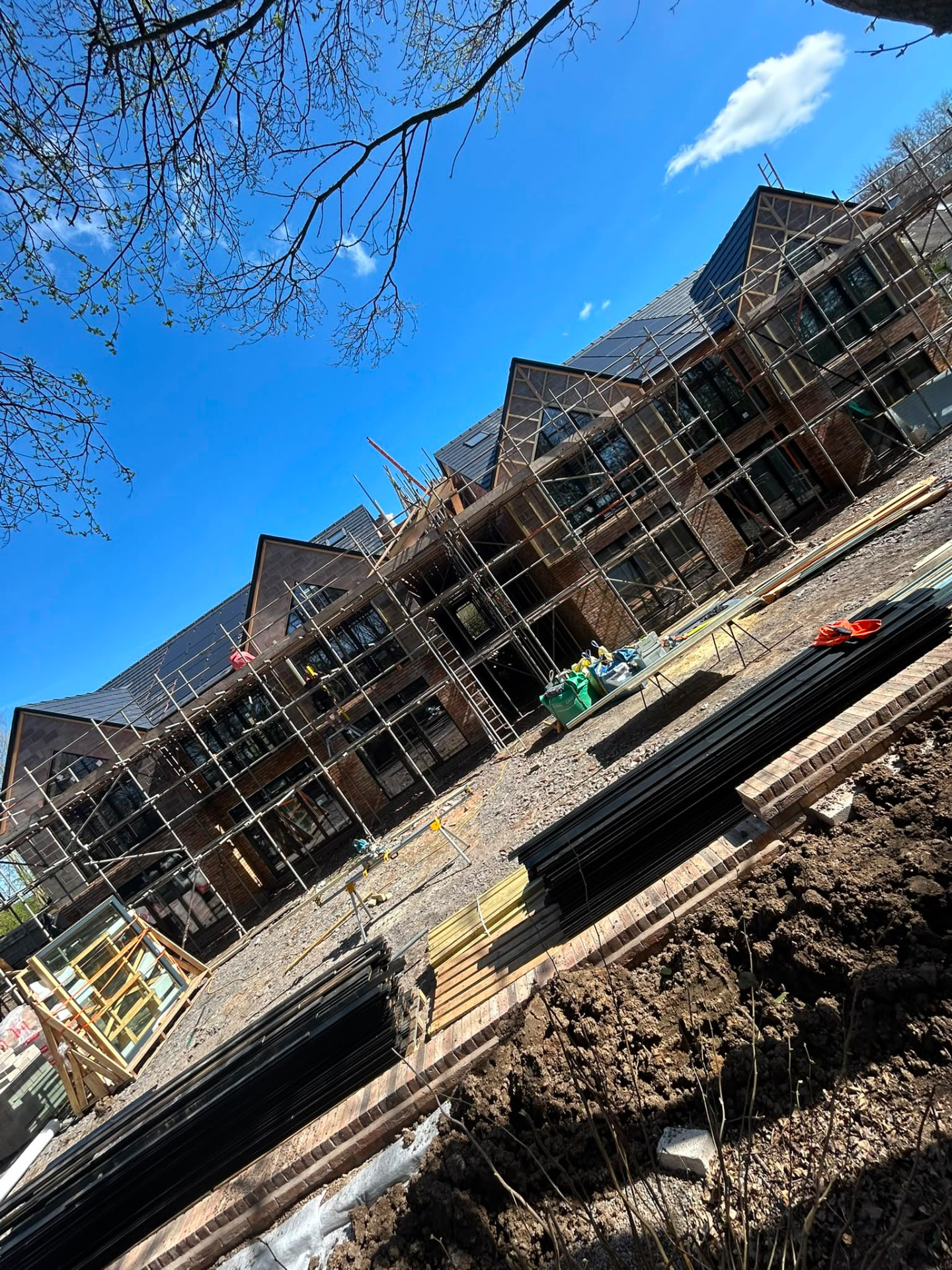 Multi-gable development under scaffold with brickwork and slate roofing complete